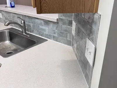 Kitchen sink with gray subway tile backsplash mid-install