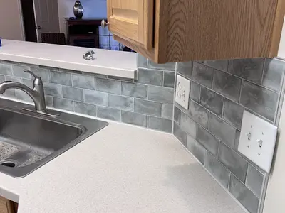 Kitchen counter sink with gray subway tile backsplash