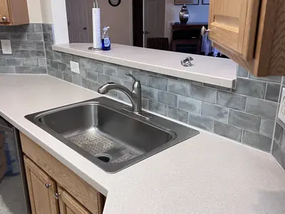 Kitchen sink countertop with gray tile backsplash