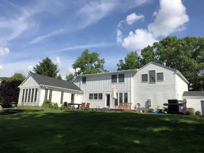 Backyard view of two-story home with deck and grill