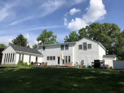 Backyard view of two-story home with patio furniture