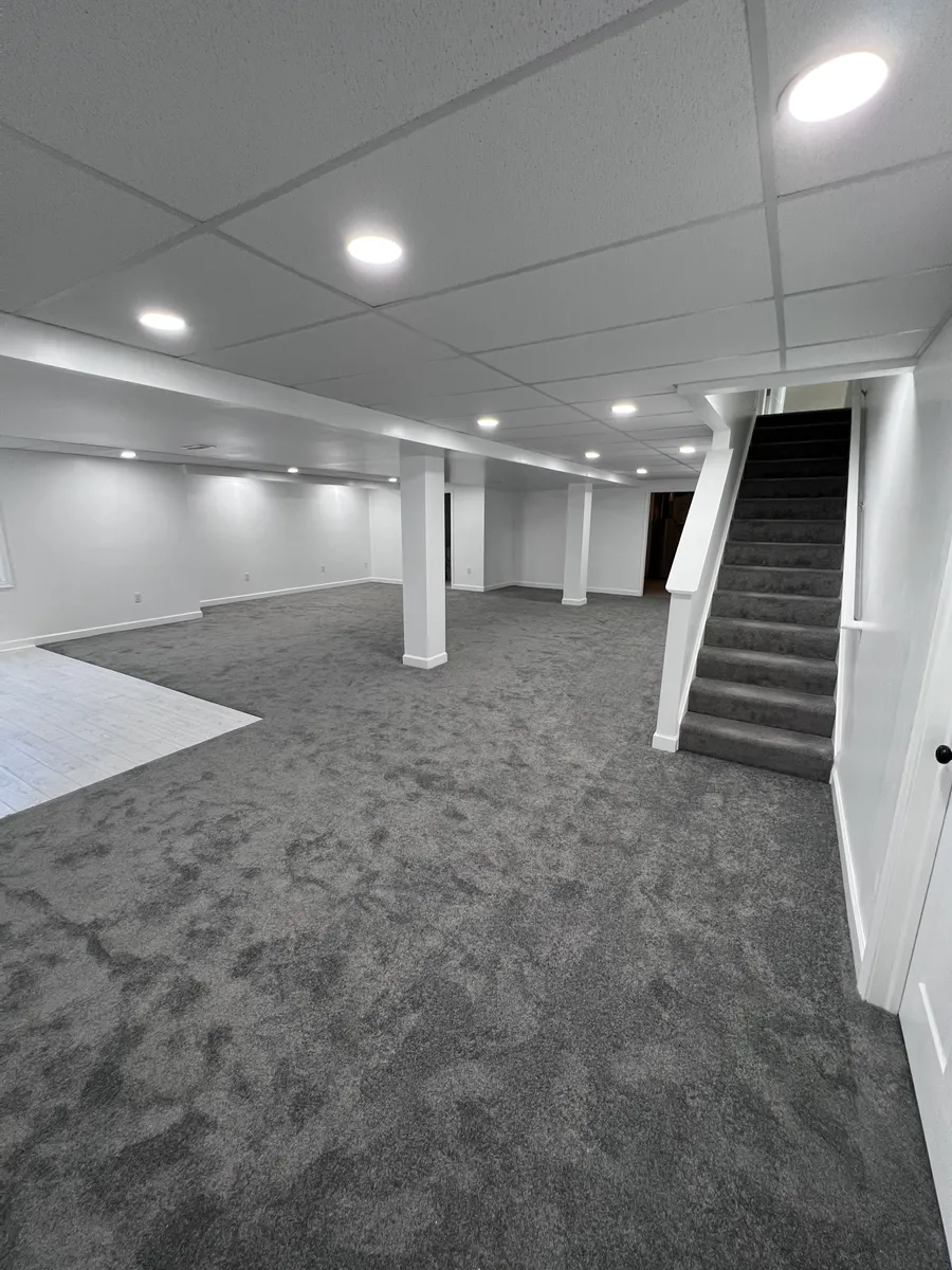 Finished basement with gray carpet and staircase