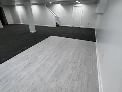 Finished basement with light wood floor and stairs