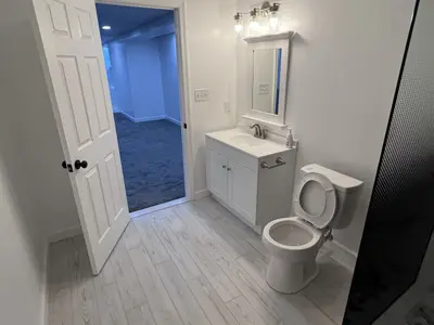 Bathroom vanity, mirror, and toilet near doorway