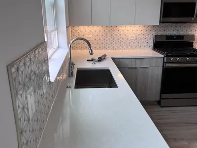 Kitchen with white quartz counters, sink, gas range