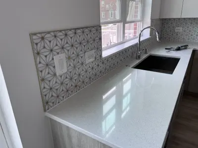 white quartz countertop with geometric tile backsplash and sink