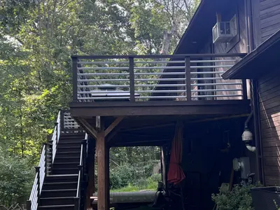 Elevated dark deck with stairs, wooded backyard view