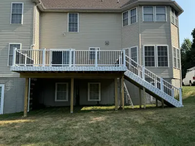 Elevated white-railing deck on tan vinyl-sided house