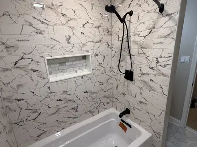 Marble-tiled shower tub with niche and black fixtures