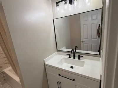 White vanity with black faucet and large mirror