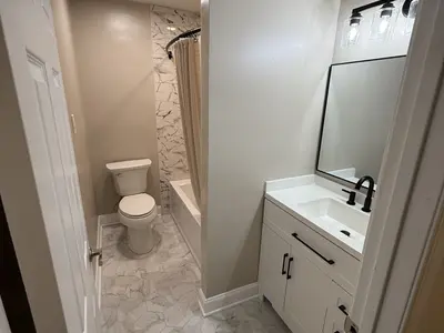 Bathroom with toilet, vanity, marble shower curtain area