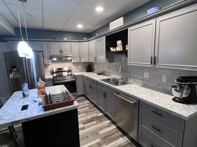 Basement kitchen with gray cabinets, island, stainless appliances
