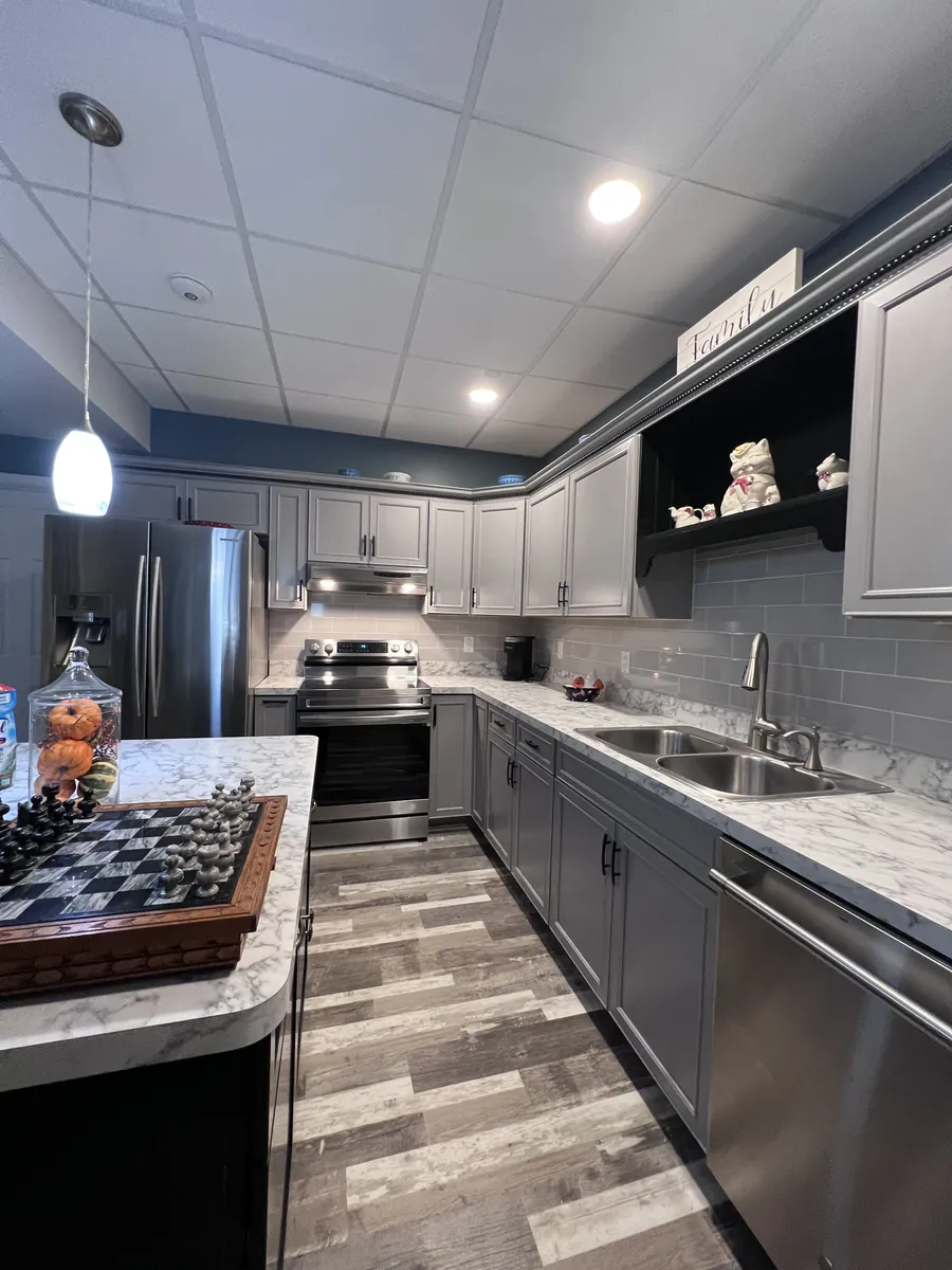 Basement kitchen with island and gray cabinets, wide view