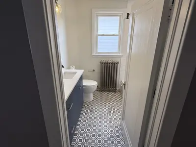 Bathroom with patterned tile floor, blue vanity, radiator