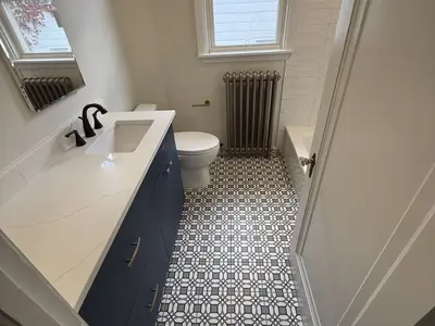 Bathroom with patterned tile floor, blue vanity, radiator