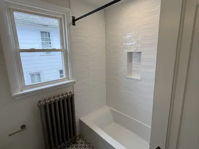 white tile tub surround with window and radiator