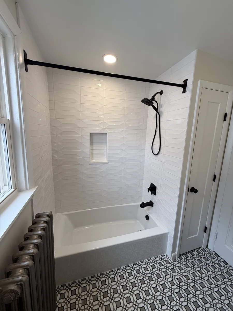 White tile tub shower with black fixtures