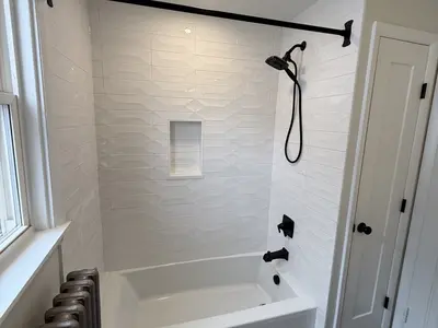 white tile tub shower with black fixtures