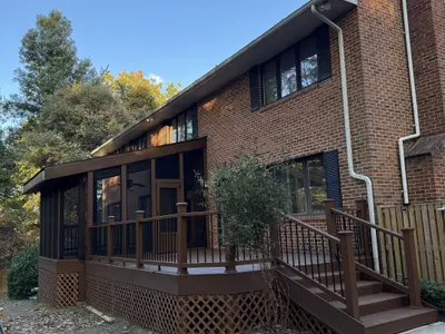 brick house with screened porch and brown deck