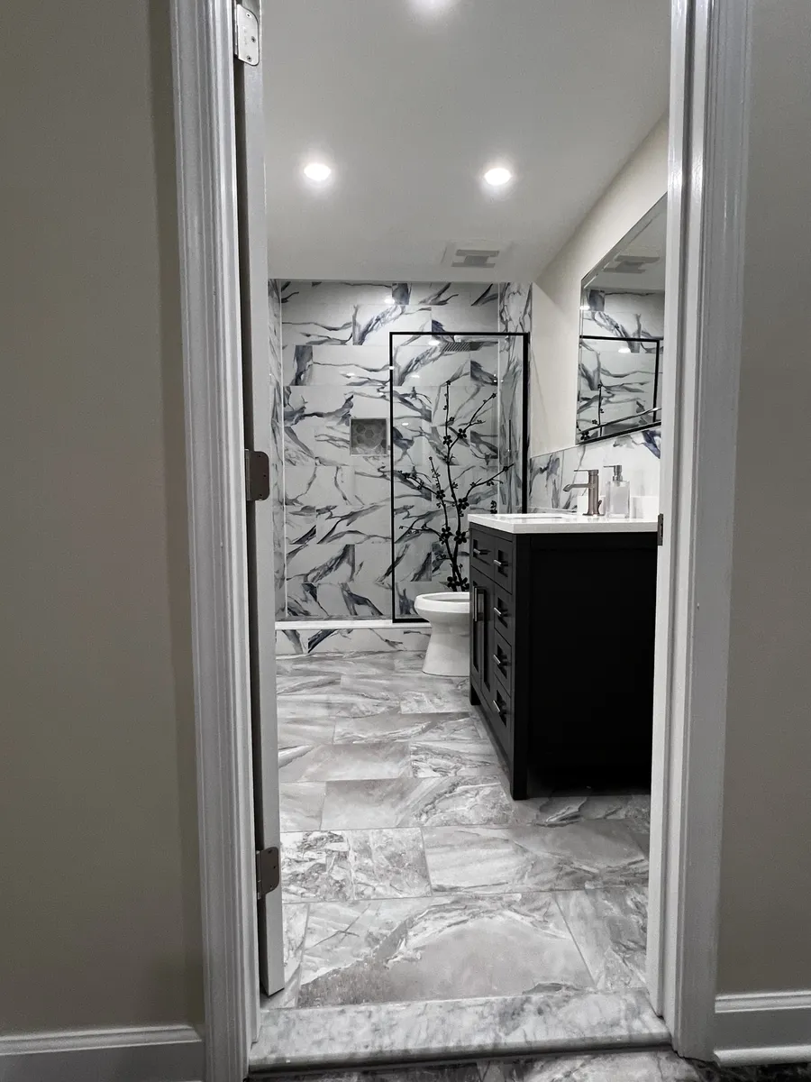 Marble-look bathroom with black vanity and walk-in shower