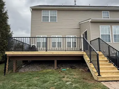New wood deck with black metal railings on home