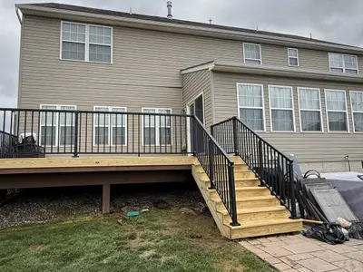 Wood deck with stairs and black railings rear of house