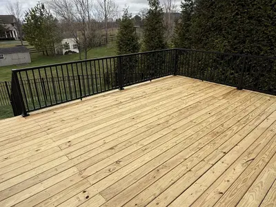 Wood deck surface with black metal railings rural view