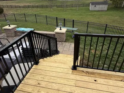 Deck stairs leading down to paver patio backyard