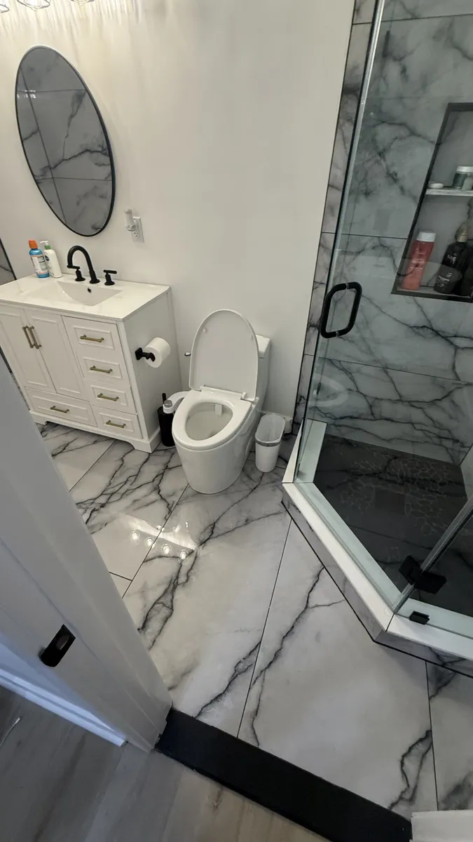 Bathroom with white vanity, toilet, and marble shower