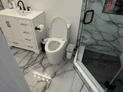 Bathroom with white vanity toilet and marble shower