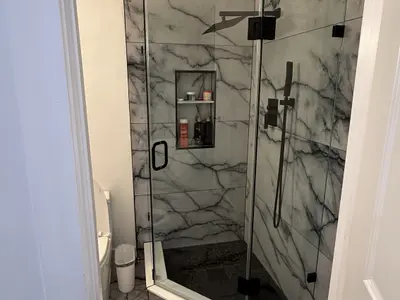 Glass marble walk-in shower with black fixtures and niche