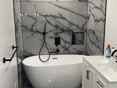 Soaking tub against marble tile wall with vanity
