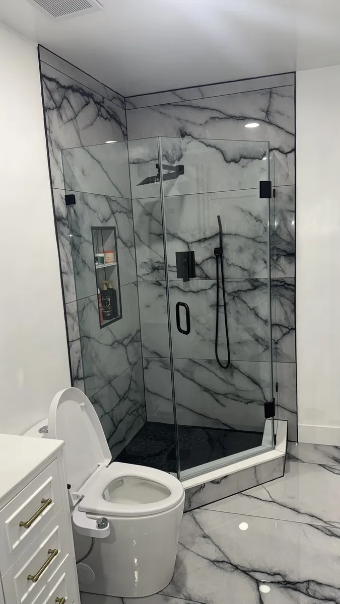 Marble walk-in shower with glass doors and black fixtures