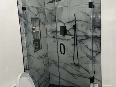 Marble walk-in shower with glass doors and black fixtures