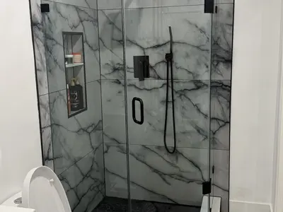 Glass marble shower with black hardware and niche