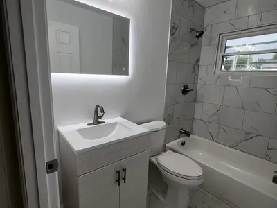 Bathroom with white vanity LED mirror tub and tile