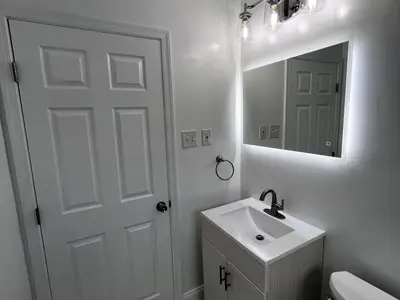Bathroom vanity with LED mirror beside white door