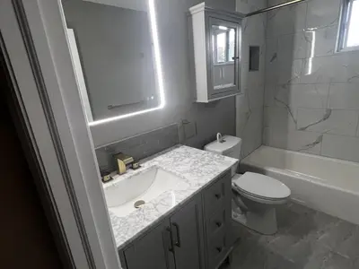 Bathroom with gray vanity LED mirror tub and tile