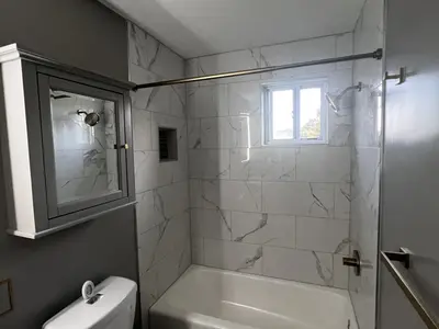 Tub with marble tile surround toilet medicine cabinet