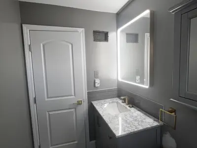 Gray vanity with LED mirror beside white door
