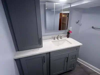 Gray bathroom vanity with mirror and tall cabinet
