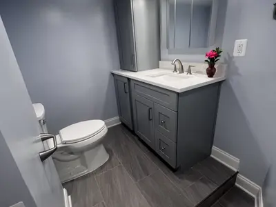 Gray vanity beside toilet with mirror and flowers