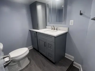 Gray vanity tall cabinet toilet on tile floor