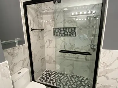 Glass walk-in shower with marble walls and mosaic floor