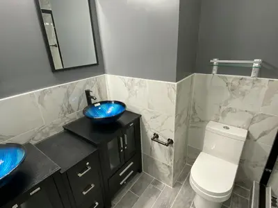 Bathroom with black vanity, blue sink, and toilet