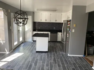 Kitchen with white cabinets, island, and dark backsplash