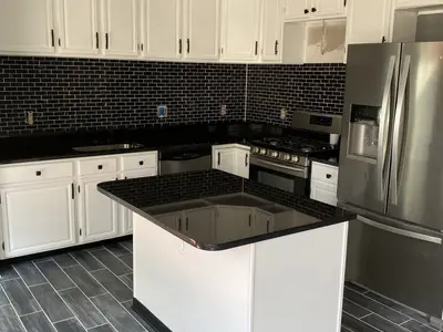 Kitchen with dark brick backsplash and black granite counters