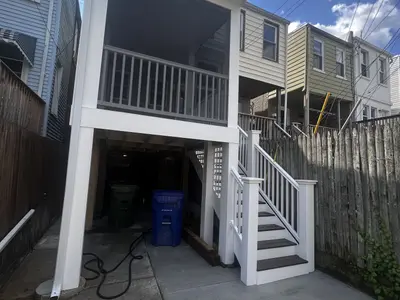 Backyard raised deck with white railing and stairs