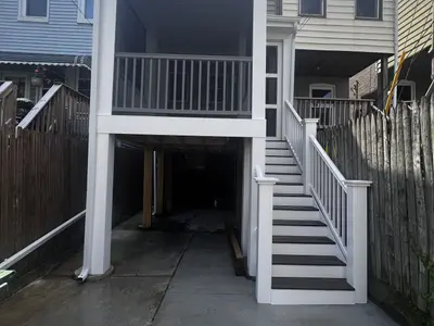 Raised deck and white stairs in narrow backyard
