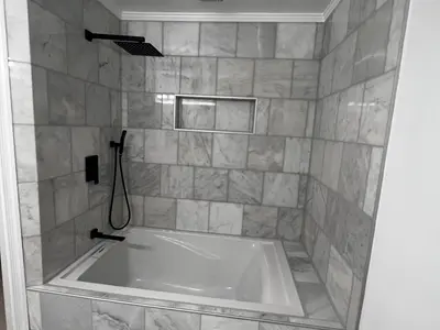 Tub and shower combo with marble tile and black fixtures